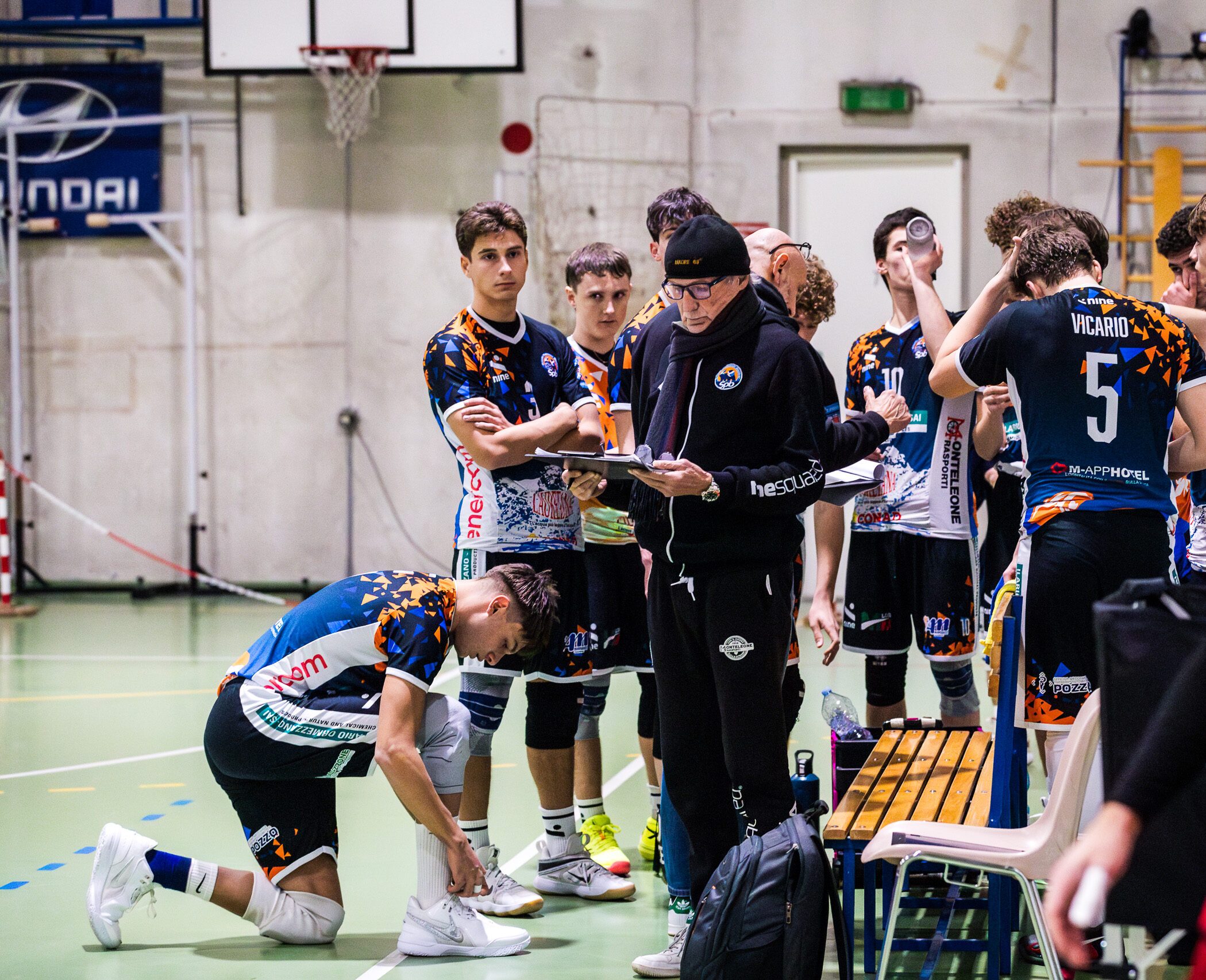 La squadra della Serie C Ilario Ormezzano SPB in palestra durante un break di partita, prevalgono colori accesi della palestra e della squadra