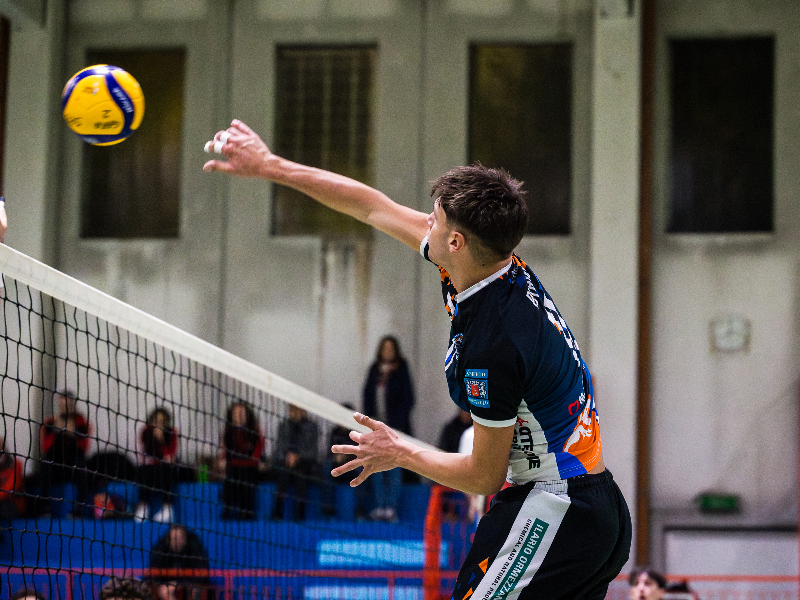 Giovane atleta pallavolista della Serie C Ilario Ormezzano mentre schiaccia sul muro degli avversari